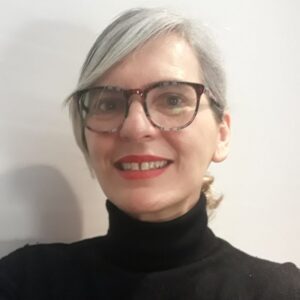 María José Nieto tiene pelo largo y canoso, gafas marrones grandes y jersey negro con cuello de cisne